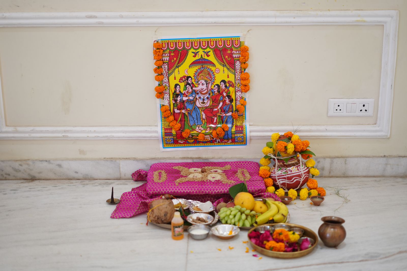 Pooja room design in a Bengaluru home 2026 with brass kalash, marigold garlands and marble flooring by myNivasa