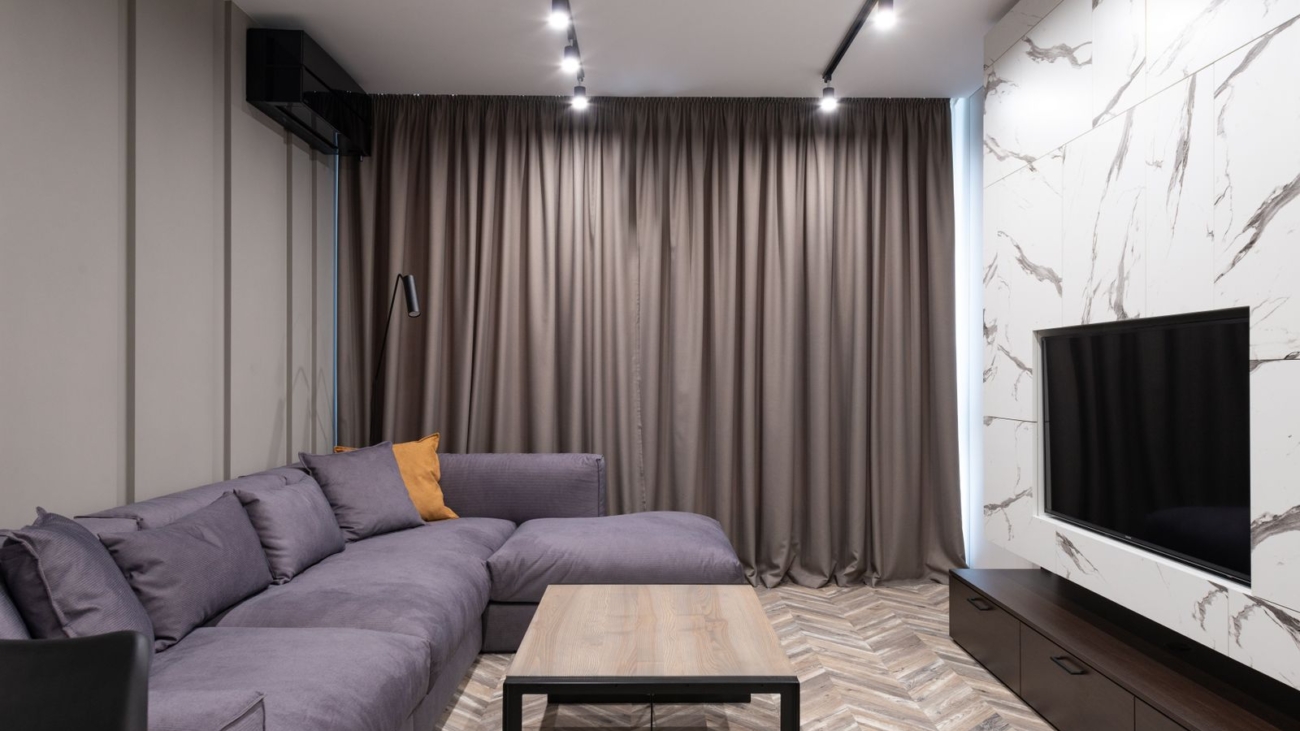 Finished modern apartment living room with corner sofa and TV panel in Bengaluru, illustrating interior payment schedule milestones 2026, by myNivasa