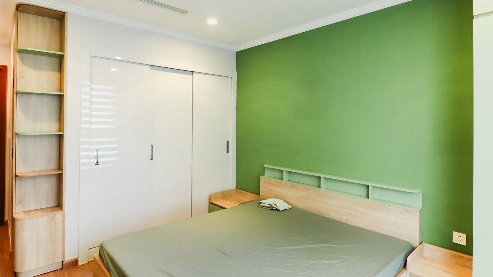 Two colour bedroom in a Bengaluru apartment with a sage green accent on the headboard wall and warm white on the wardrobe wall, 2026, by myNivasa