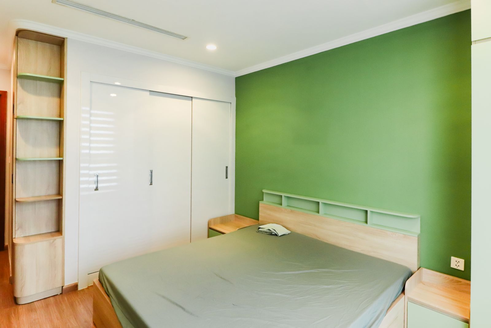Two colour bedroom in a Bengaluru apartment with a sage green accent on the headboard wall and warm white on the wardrobe wall, 2026, by myNivasa