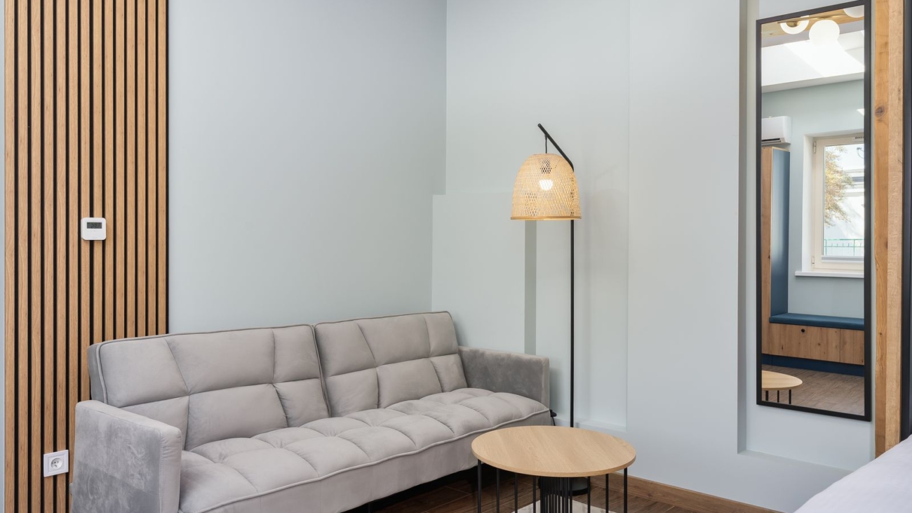 Living room feature wall with vertical fluted wood slat panelling beside a grey sofa in a Bengaluru apartment, 2026, by myNivasa