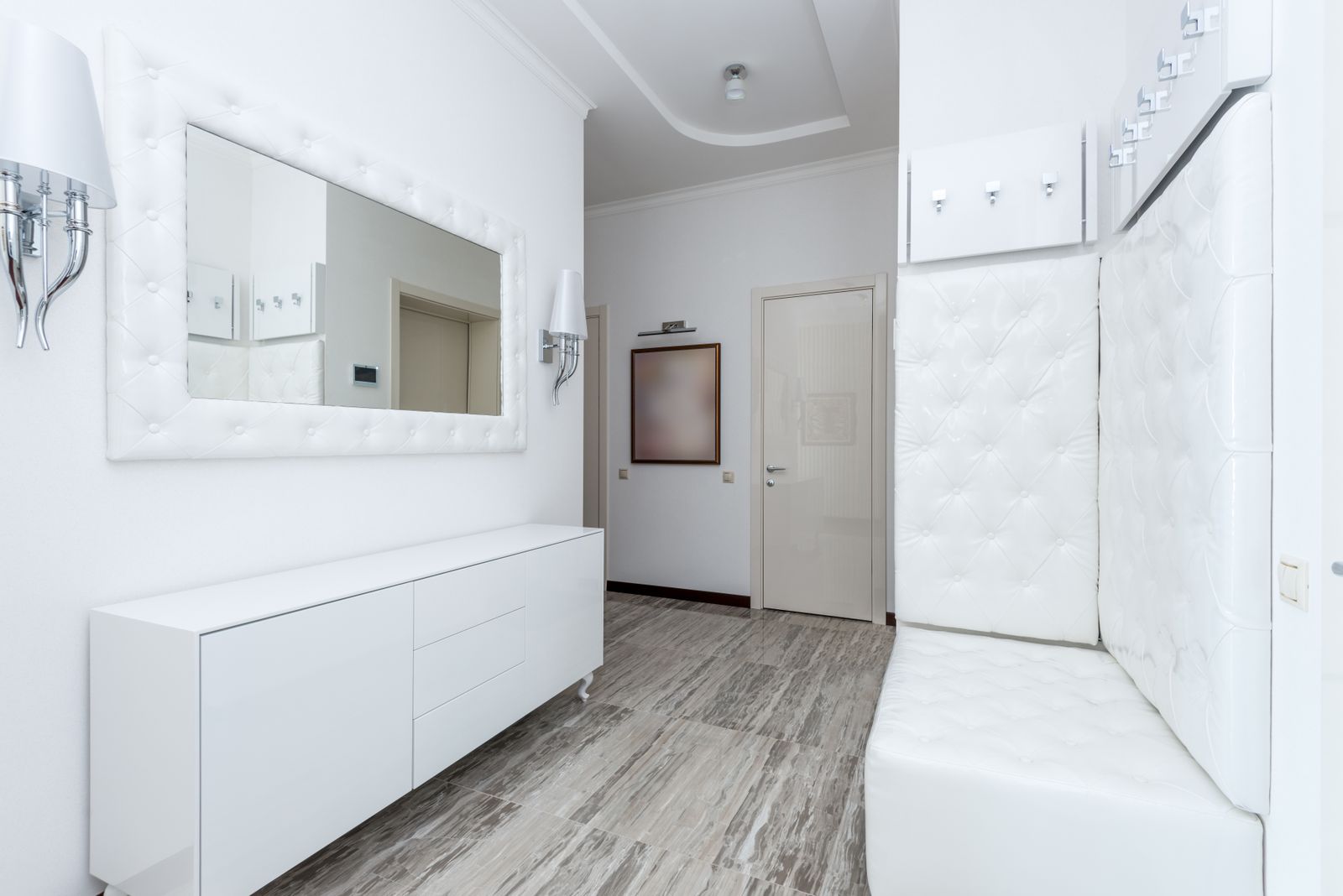 Long low white entrance cabinet with flat internal shelves running along a hallway wall opposite a mirror, entrance shoe cabinet cost Bengaluru 2026, by myNivasa