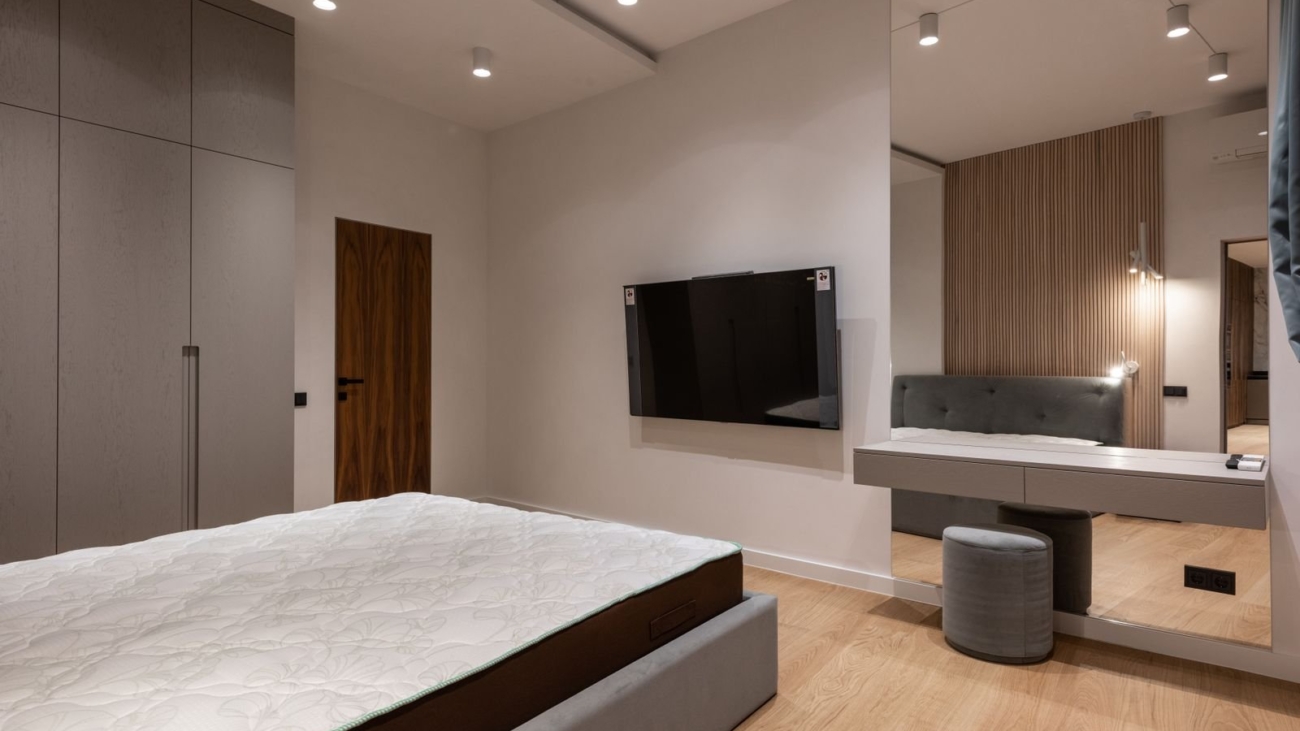 Bedroom with a floating wall-mounted dressing counter, tall mirror and grey stool beside a wardrobe, Bengaluru bedroom design 2026 by myNivasa