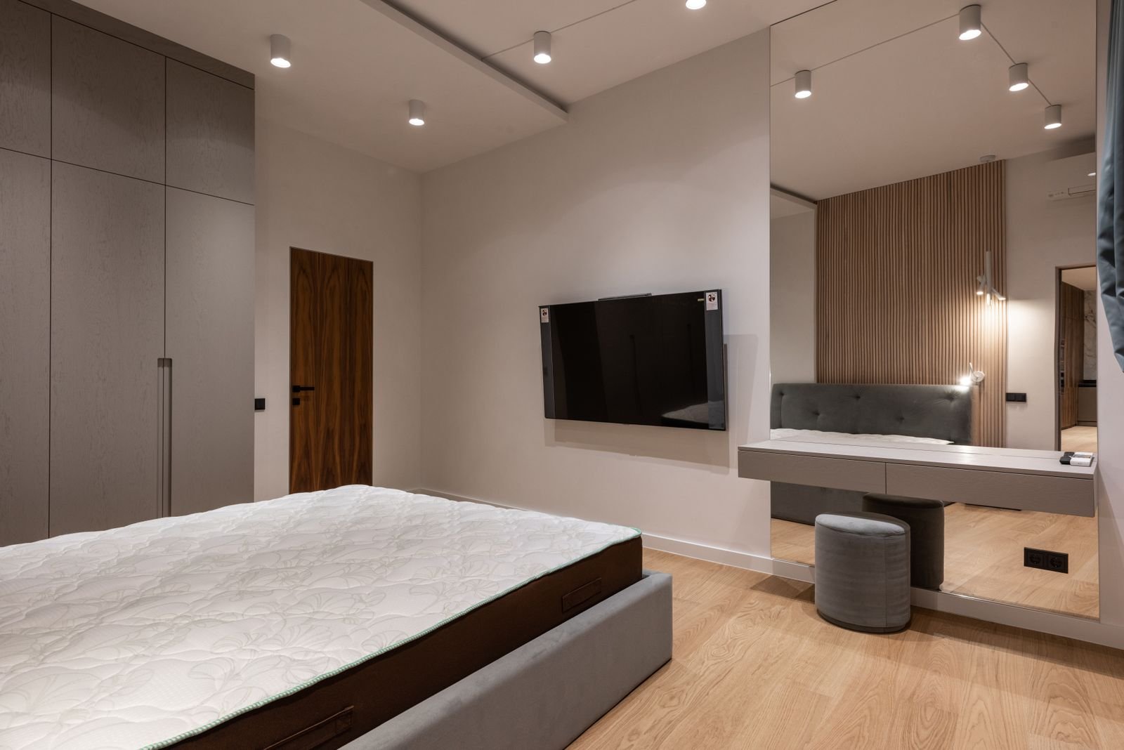 Bedroom with a floating wall-mounted dressing counter, tall mirror and grey stool beside a wardrobe, Bengaluru bedroom design 2026 by myNivasa