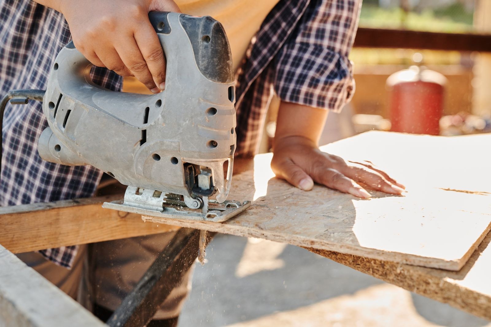 Carpenter cutting a board with a jigsaw outdoors, showing a raw cut edge before edge banding, kitchen cabinet edge guide for Bengaluru 2026, by myNivasa