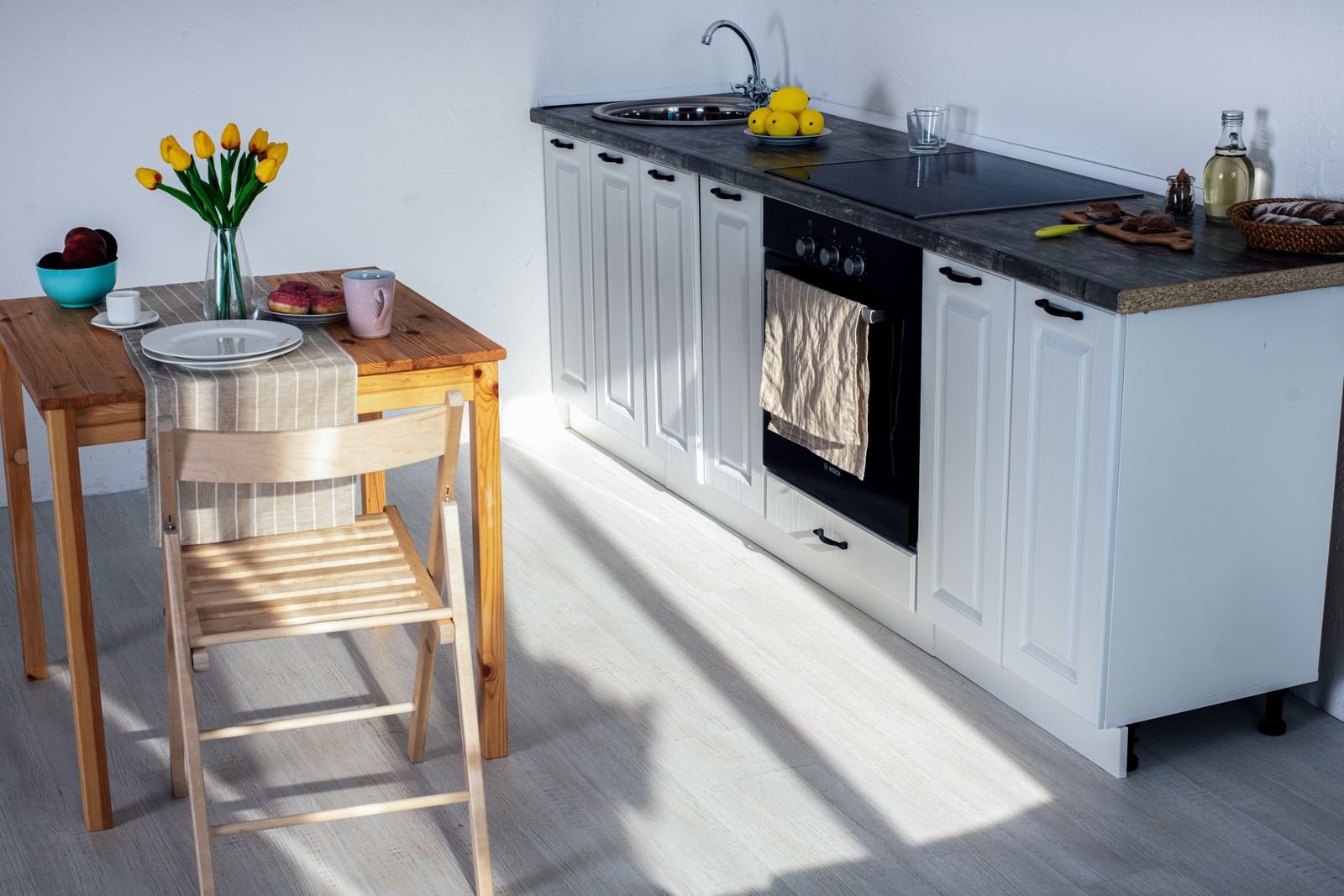 White base cabinets with a recessed plinth gap above a light floor in a compact Bengaluru kitchen, plinth height and material guide 2026, by myNivasa