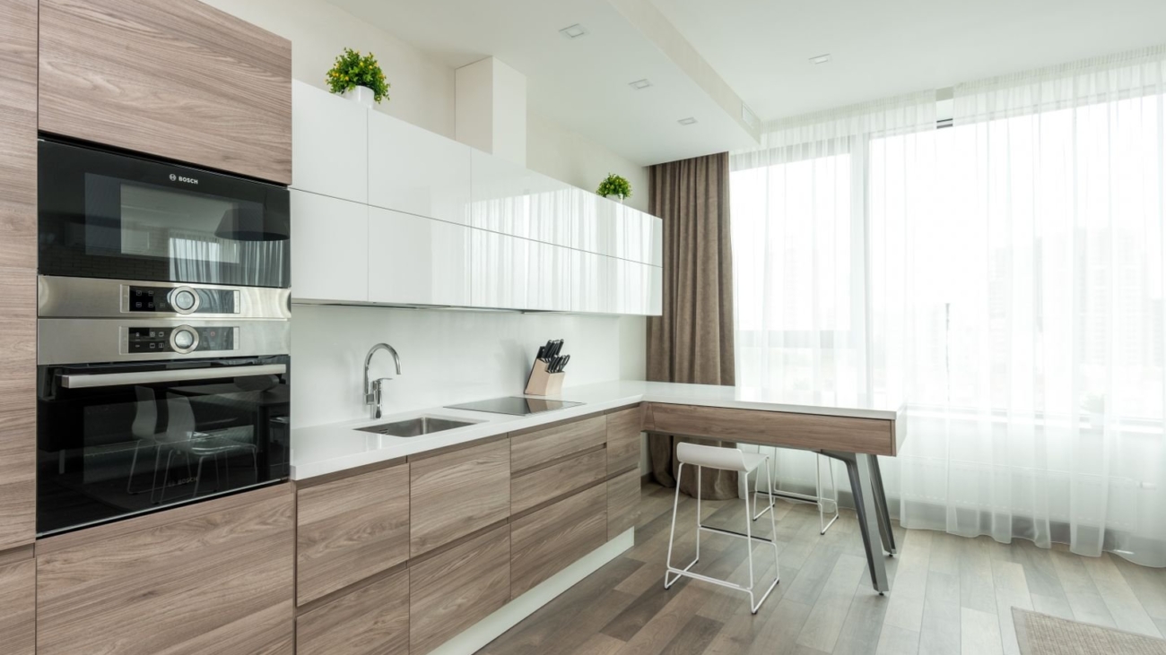 Modern Bengaluru kitchen with wood-grain base cabinets, white upper cabinets and a clean plinth line at the floor, plinth material guide 2026, by myNivasa