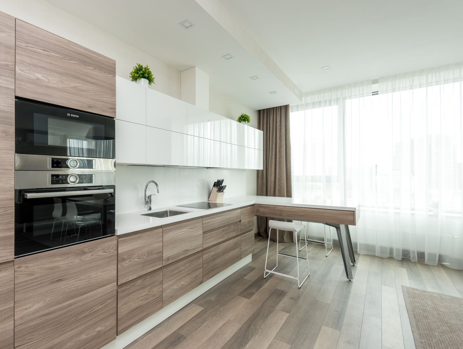Modern Bengaluru kitchen with wood-grain base cabinets, white upper cabinets and a clean plinth line at the floor, plinth material guide 2026, by myNivasa