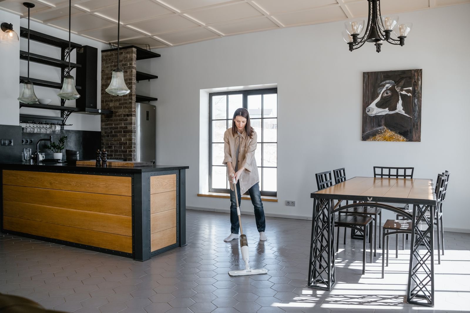 Woman mopping a tiled floor beside a kitchen counter in a Bengaluru style open plan home, mop water and kitchen plinth damage guide 2026, by myNivasa