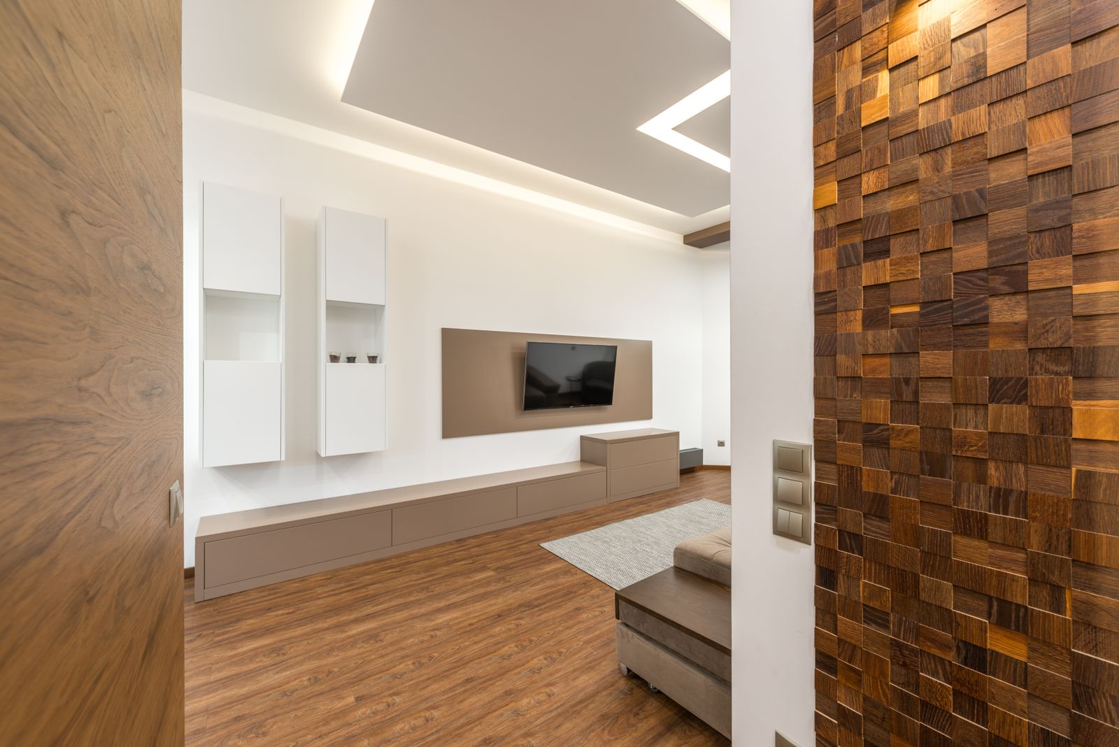 Bengaluru living room with a wall-mounted TV panel, white wall cabinets and a wooden feature wall, choosing a pooja corner wall in a 2BHK, 2026, by myNivasa